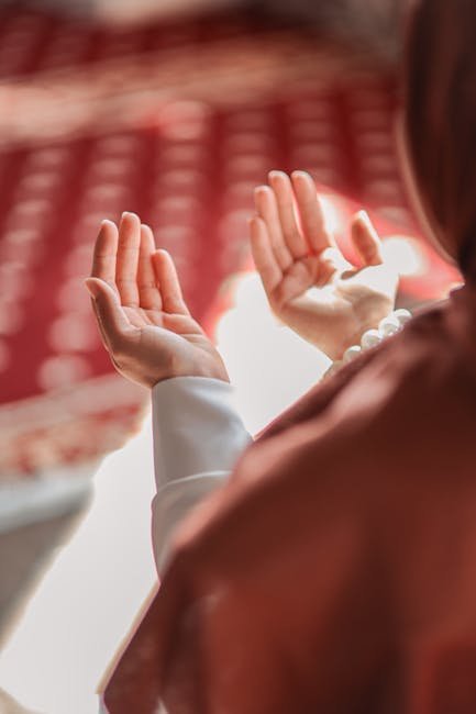 Muslim woman praying in a mosque, hands raised in devotion, emphasizing spirituality and faith.