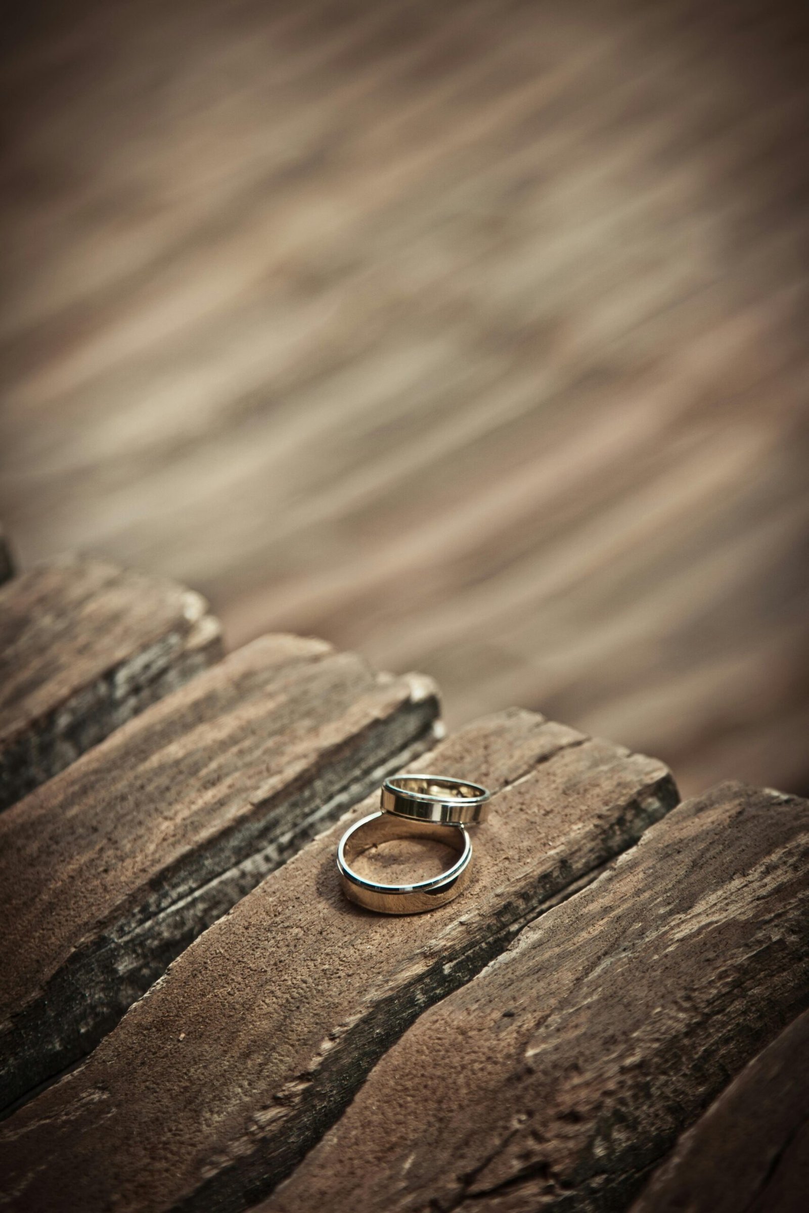 Close-up of elegant silver wedding rings on a rustic wooden surface, symbolizing love and unity.